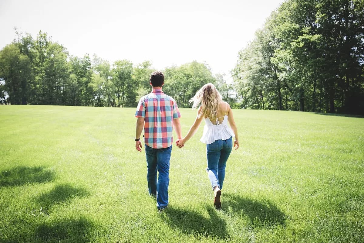 Illustrative stock photograph of two adults walking hand in hand through a sunlit park