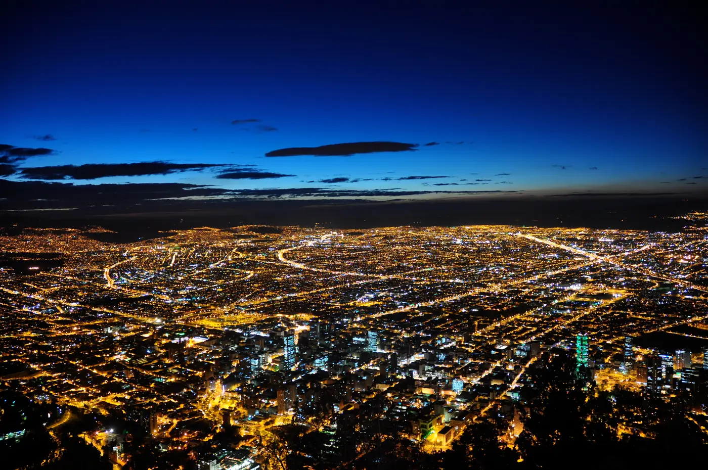 Bogotá city lights beneath a deep blue evening sky
